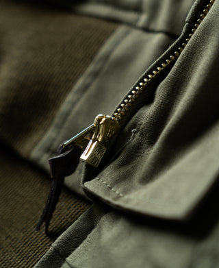Olive flight jacket front zipper with brass pull and covered placket