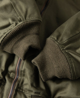 Olive flight jacket cuff with rib knit trim and visible front zipper.