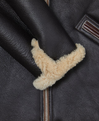 Dark leather flight jacket sleeve cuff with cream shearling trim and zipper