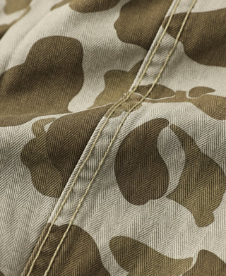 Camo fabric close-up with visible stitching and buttonhole thread.
