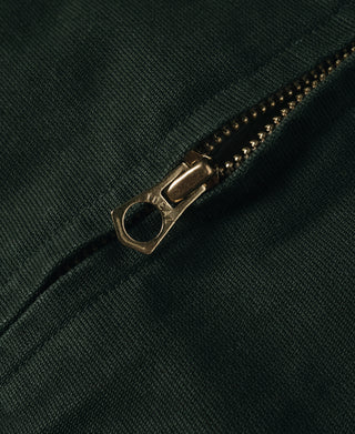 Dark green jacket zipper with gold-toned pull and metal slider detail