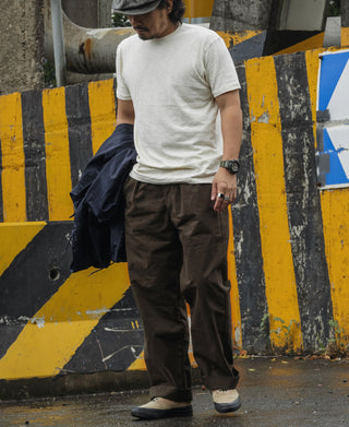 Dark brown combat pants on model with roomy straight legs and cuffed hem