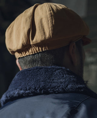 Khaki biker cap with ribbed brim and contrast dark inner lining.