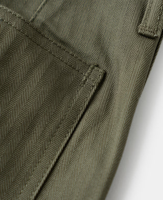 Olive trousers side seam close-up with small button and bartack stitching