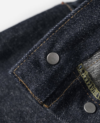 Indigo denim jeans pocket close-up with round metal button and orange-brown stitching