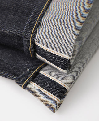 Selvedge denim hem close-up with stitched inner edge and exposed orange-brown thread