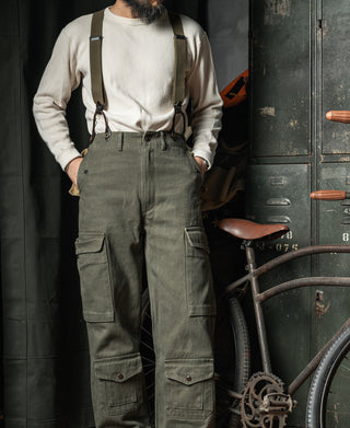 Olive canvas back suspenders worn over a light shirt and olive trousers