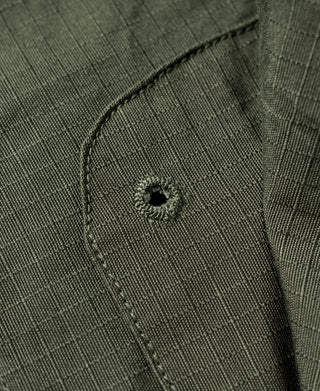 Olive fatigue jacket placket close-up with round black button and stitched seam