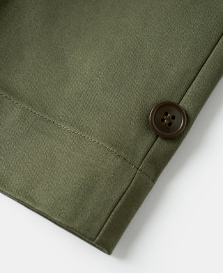 Olive trouser front with dark button fastening and vertical seam.
