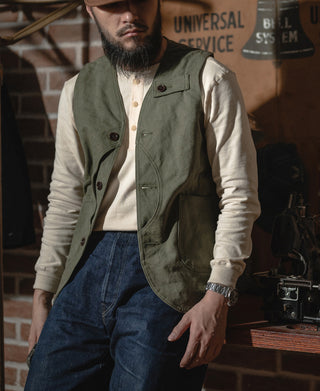 Apricot henley shirt with button placket and ribbed collar, worn under green vest