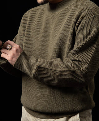 Olive crewneck wool sweater detail with ribbed cuffs and textured knit.