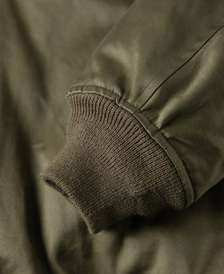 Olive flight jacket sleeve cuff with rib knit hem and seam stitching.
