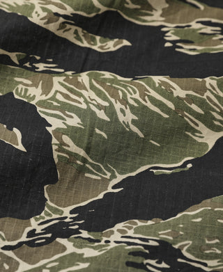 Tiger stripe camo fabric close-up with dark, green, and tan shapes.