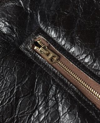 Dark brown leather flight jacket zipper with brass-toned pull and label tab