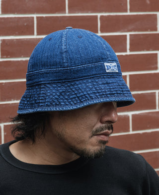 Indigo denim bucket hat with front patch visible on a model