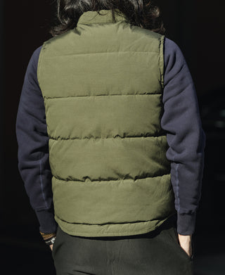 Olive quilted padded vest back view on a person over long sleeves