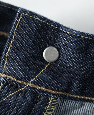 Indigo denim jeans pocket corner with silver button and gold-orange stitching