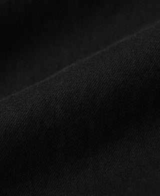 Black denim jacket fabric close-up with fine textured weave
