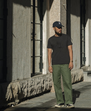 Olive trousers worn with sneakers; straight wide-leg cut with visible waistband and pockets