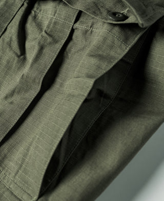 Olive fatigue pants pocket and fly area close-up with button detail