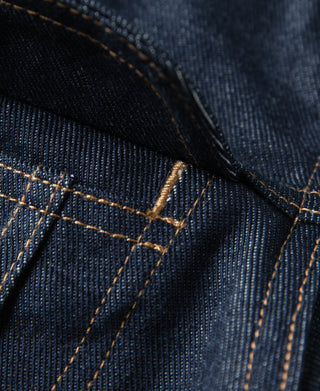 Indigo denim jacket seam detail with contrast tan topstitching and folded panel
