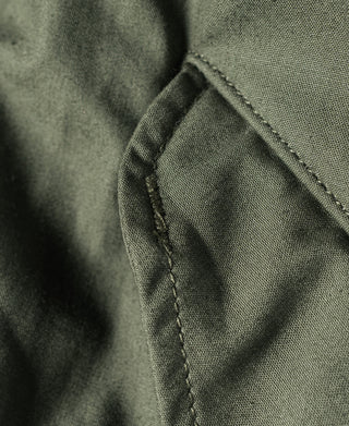 Olive M-65 parka side tab with stitched border and folded fabric edge