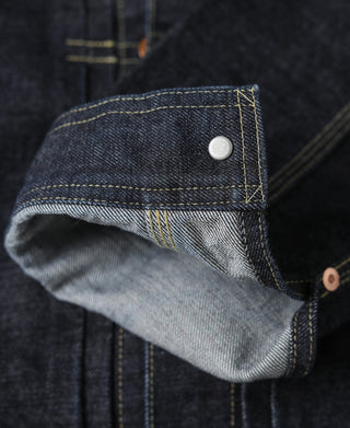Indigo denim jacket cuff with small white snap button and rolled denim hem