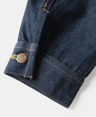 Indigo denim jacket cuff with gold-tone brand rivet and stitched hem edge