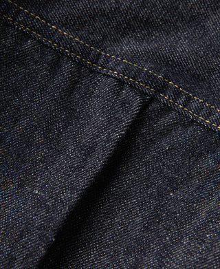 Indigo denim jacket close-up of diagonal seam and gold contrast topstitching.