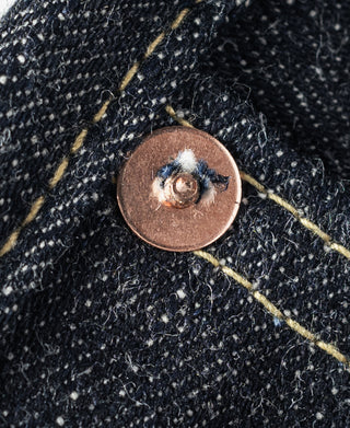 Indigo denim jeans close-up of copper button on a stitched panel