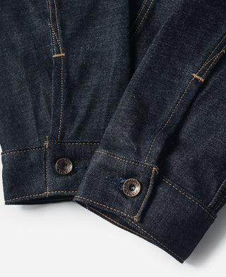 Indigo denim jacket cuff with two metal buttons and contrast orange topstitching