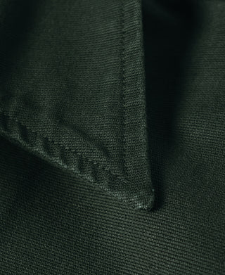 Dark green jacket sleeve cuff with folded seam and small stitched panel