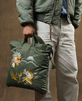 Olive embroidered helmet bag with dragon and tiger graphic, held by top handle