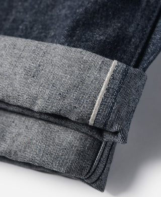 Cuffed hem detail on dark navy denim pants with inner seam stitching