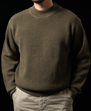 Olive crewneck wool sweater on model, textured knit and ribbed collar.