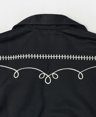 Black jacket back with cream zipper-like trim and decorative loop embroidery