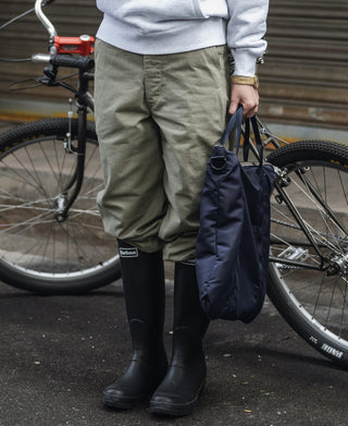 Navy helmet bag held at the handle, with front pocket