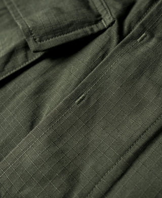Olive fatigue jacket sleeve cuff with stitched fold and hidden button placket