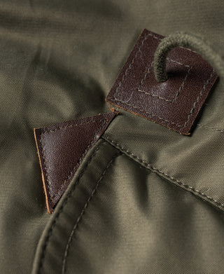 Olive N-3 parka with brown leather patch tabs on the front placket seam.