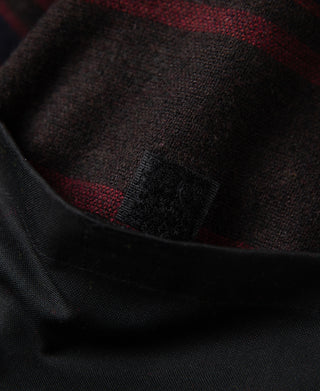 Black waxed jacket inner lining with red-and-black plaid fabric at collar