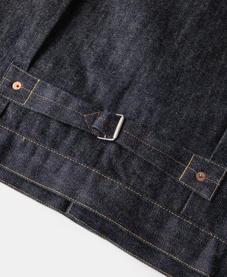Indigo denim jacket lower pocket flap with metal snap and gold bar-tack stitching.