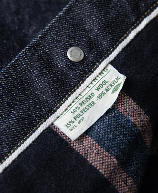 Indigo denim jacket interior label with circular button and plaid blanket lining