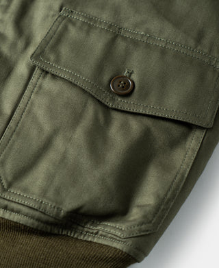 Olive flight jacket chest pocket with button closure and reinforced stitching