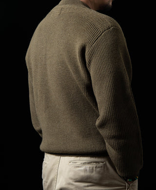Olive crewneck wool sweater on model, side view with ribbed sleeve cuffs.