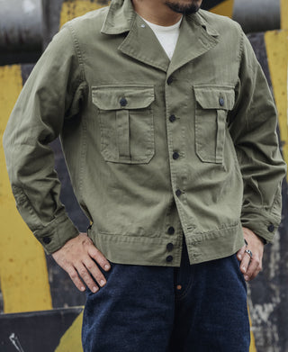 Olive fatigue jacket worn by model with button front and flap chest pockets