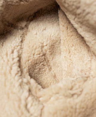 Cream shearling interior of a dark brown flight jacket collar lining