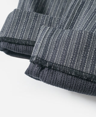 Cuffed hem of black and gray striped pants with stitched bottom edge