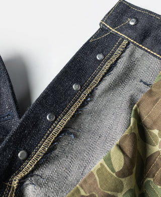 Indigo denim jeans waistband area with buttoned placket and yellow stitch trim