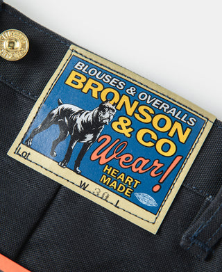Navy canvas pants with branded waist label and gold snap closure