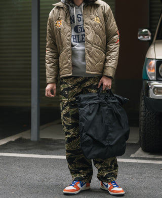 Black nylon helmet bag with wide body, carried by strap